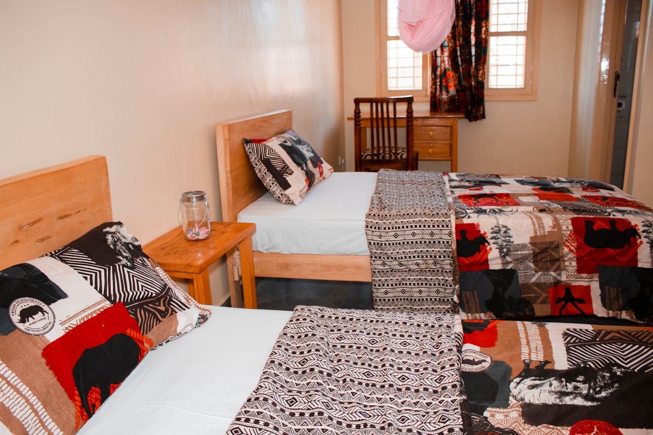 Colorful twin bedroom with unique African quilts and wooden furniture in Kampala, Uganda.