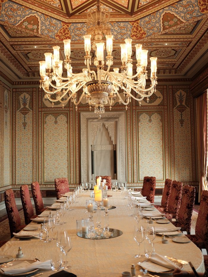 Opulent dining room featuring a grand chandelier and ornate decor.