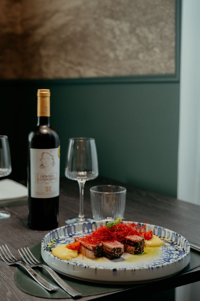Elegant gourmet dish with red wine in a cozy Calabria restaurant setting.